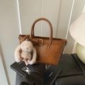 Bolso de mano marrón con hebilla dorada y colgante de conejo de peluche en un libro - Marrón con colgante