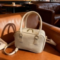 Sac à main Boston beige avec texture à vagues et fermetures dorées sur canapé cuir - Blanc Cassé