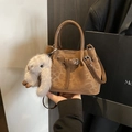 Braune Wildleder-Eimertasche mit glänzenden Ledergriffen und süßem Hasenanhänger - Braun mit Anhänger