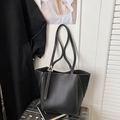 Detail van de zwarte lederen tote bag met contraststiksels en een driehoekige metalen gesp - Zwart