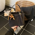 Retro coffee bucket bag with matte finish and wooden bead pendant held by a model - Brown