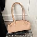 Beige baguette tas van kiezel leer met zilveren hardware op koffer en boeken - Khaki