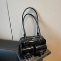 Glossy black vintage Boston bag with dual buckled front pockets and long shoulder straps - Black