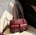 Vintage burgundy Boston pillow bag with glossy finish and silver buckle pockets on car seat - Burgundy