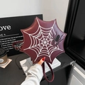 Detail of burgundy spider web handbag featuring white embroidery and 3D spider decor - Red