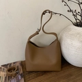 Detail of a brown lychee-textured leather bucket bag with silver metal buckle - Brown