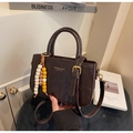 Detail of dark brown crocodile-textured leather handbag with gold lettering and beaded charm - Coffee (With Pendant)
