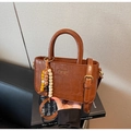 Detail of brown crocodile pattern handbag with elegant beaded pendant and slim strap - Yellow Brown (With Charm)