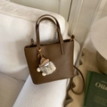 Sac seau en cuir litchi marron avec un pendentif peluche sur un canapé blanc - Marron