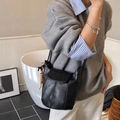 Borsa a secchiello retrò in pelle nera con ciondolo in legno, indossata da una modella - Con Ciondolo / Nero