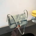 Retro Umhängetasche in Denimblau mit Vintageschnalle und schmalem Riemen in der Hand - Blau