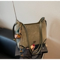Olivgrüne matte Hobo-Tasche mit Goldlogo und Blumenquaste auf Büchern präsentiert - Grün (Mit Anhänger)