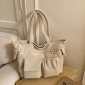 Dettaglio della borsa tote in velluto a coste beige con tasche e trama morbida - Bianco