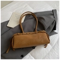 Detail of tan cylindrical shoulder bag with adjustable gold buckle on white textured surface - Large / Brown