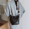 Schwarze Bucket Bag aus Leder mit Retro-Textur und kariertem Gurt getragen von Model - Schwarz