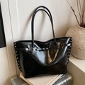 Large black tote bag with silver studs and glossy finish on a minimalist background - Black