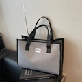 Grey checkered tote bag with black handles and Murer BAGS label on a book - Gray