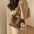 Detail der dunkelbraunen Eimertasche mit Litschi-Struktur und süßem Plüschhund-Anhänger - Ohne Anhänger (Mit Untertasche) / Kaffee