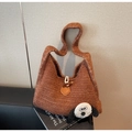 Gros plan sur la texture du sac en tricot caramel avec écusson cartoon et bouton en corne - Marron