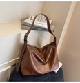 Detail of a brown leather shoulder bag with gold hardware on a corduroy stool - Brown