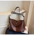 Detail of dark brown PU leather tote bag with pleated design on a black leather seat - Brown