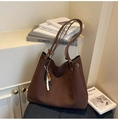 Détail d'un sac cabas en daim marron avec un charm en perles colorées sur la poignée - café