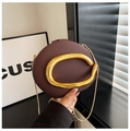 Macro detail of wine red matte leather bag featuring an elegant gold C-shaped metal buckle - Brown