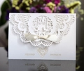Detalle de invitación de boda calada con láser con lazo de satén y letras doradas - Blanco