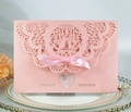 Rosa lasergeschnittene Hochzeitseinladung mit Seidenschleife und Perlen auf Teller - Rosa