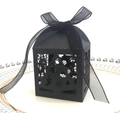 Macro view of a black laser-cut Christmas tree gift box with elegant organza ribbon on a plate - Black Khaki