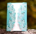Macro view of laser-cut light blue wedding invitation with butterfly and flower patterns - Tiffany Blue