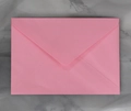 Detailed top view of a classic pink paper envelope with a V-shaped flap on marble surface - Crimson Rectangular