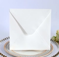Close-up of white square V-flap invitation envelope on a decorative white dinner plate - Square White
