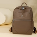 Detailed macro view of the brown lychee grain texture and silver metal rabbit logo on backpack - Brown