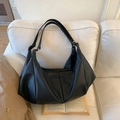 Bolso hobo negro plisado con textura granulada sobre un sofá crema con gabardina - Negro