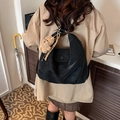 Borsa a spalla nera opaca con ciondolo a forma di orsetto indossata da modella in beige - Nero con ciondolo