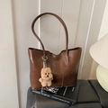 Borsa tote marrone in pelle con ciondolo a forma di peluche su scrivania moderna - Beige Cachi Con Ciondolo