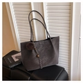 Dettaglio della borsa tote in pelle scamosciata grigio scuro con logo e ciondolo pompon - Con Ciondolo / caffè