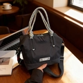 Schicke schwarze Nylontasche mit dreifarbigem Flechtgriff auf einem Café-Tisch - Schwarz