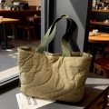 Olijfgroene gewatteerde nylon shopper op een houten tafel in een gezellige koffiebar - Groen