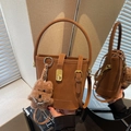 Brown bucket handbag with gold buckle and cute teddy bear charm on a mirror surface - Brown with Pendant