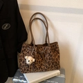 Detail of leopard print tote bag with brown straps and plush bear charm on a suitcase - Leopard Print Brown With Pendant