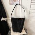 Detail einer minimalistischen schwarzen Leder-Eimertasche auf einem Metallkoffer im Büro - Schwarz