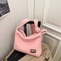 Borsa tote rosa in peluche con patch TXBD appesa a una valigia in un contesto di viaggio - Rosa