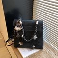 Black matte backpack with star patch, braided handle and cat charm in a home setting - Black (With Charm)