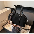 Details der schwarzen Boston Bag in Geschenkbox mit glänzenden Griffen und Anhänger - Schwarz mit Anhänger