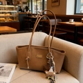 Brown vintage leather tote bag for women with decorative charms on a sofa - With Charm / Brown