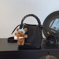 Black pebbled leather bucket bag with woven handle and brown plush bear charm accessory - Black with Pendant