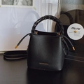 Minimalist black bucket bag featuring textured leather and a unique woven handle design - Black without Pendant