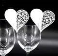 Close-up of white laser-cut heart place cards with intricate floral patterns on a glass - White